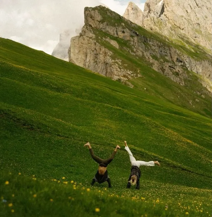 Dos personas haciendo acrobacias en un cerro verde